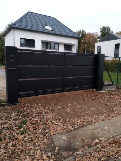 Moderne zwarte aluminium schuifpoort met horizontale lamellen en dichte panelen voor een oprit.