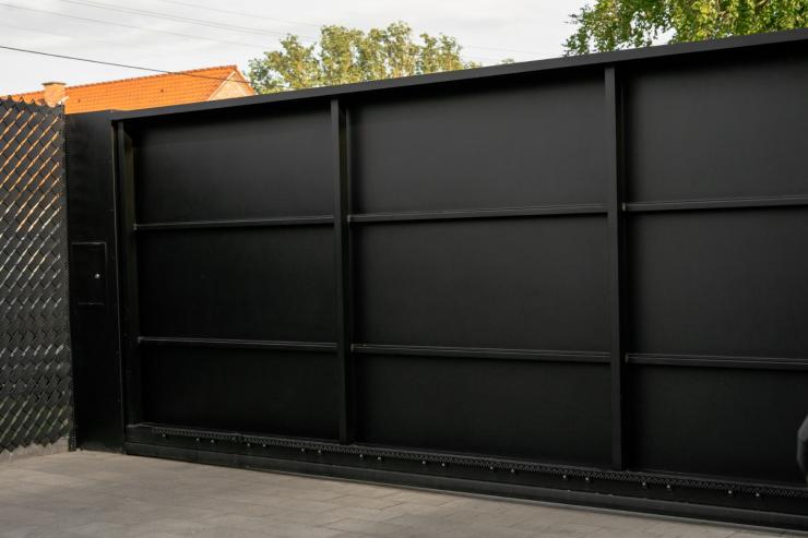 Moderne zwarte schuifpoort met brievenbus bij witte woning