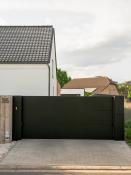 Moderne zwarte schuifpoort met brievenbus bij witte woning